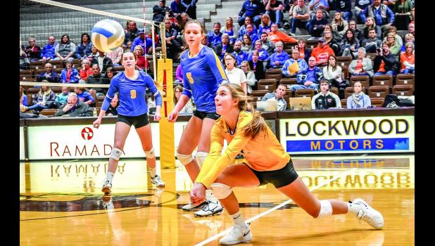 Photo for the Mascot by Brian Jeremiason Abby Hennen digs out a shot with Lydia Sussner (5) and Morgan Kockelman (9) watching.
