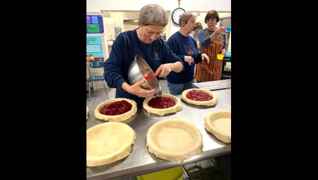 Contributed photo Kathy Wyffels pours cherries into prepared pie crusts.