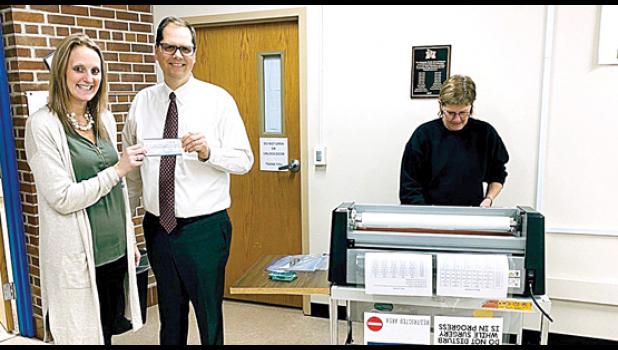 Special Photo. Sarah Stassen presented a check from the Minneota PTA to Superintendent Dan Deitte for $1,500 to go towards a new laminator. Kathy Fier (right) does the laminating for teachers. The old laminator wasn’t getting the job done anymore, said Deitte. The teachers are very thankful for the new one, he indicated.