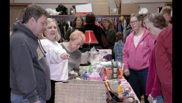 Staff Photo by Byron Higgin. Robin Traen pointed to merchandise on the table as husband Steve and mother Arla Boe looked on. Ruth Bot was also eyeing the merchandise.