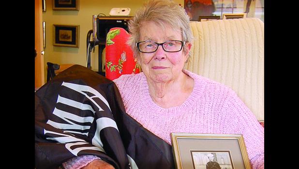 Staff Photo by Scott Thoma. Elaine Johnson clutches a photo of her brother, Earl Halvorson, and the POW/MIA flag that she hung on her front door every Memorial Day.