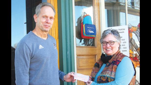 Mascot photo by Scott Thoma Joel Skillings, left, hands Minneota librarian Gail Perrizo a check to purchase children's books in a tribute to his late wife Jackie.