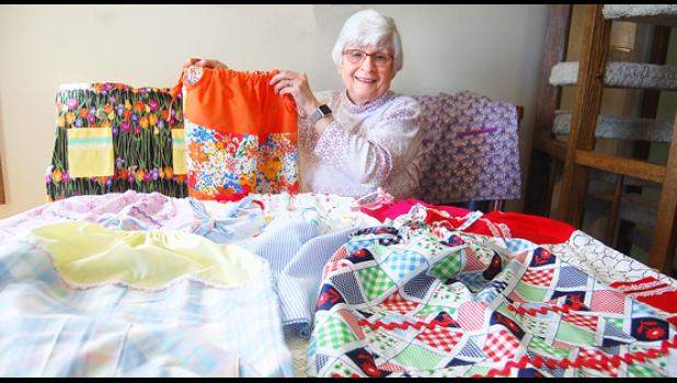 Staff photo by Scott Thoma. Terry Van Keulen, coordinator of the Council of Catholic Women sewing project, showed off several of the 268 dresses that have been sewn for the “Little Dresses for Africa” program.