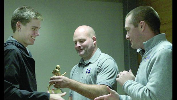Staff Photo by Byron Higgin Thomas Hennen was all smiles as he accepted his Most Valuable Teammate trophy from Offensive Coordinator Matt Myrvik. Looking on was assistant Coach Jordan Fink.