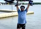 Traen raises his bike above his head before following tradition and dipping the front tire in the Mississippi River upon completion of the ride.